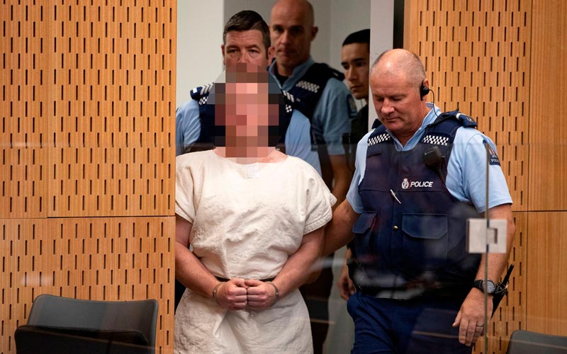 Brenton Tarrant é acompanhado por policiais durante sua apresentação à corte do Distrito de Christchurch, na Nova Zelândia, no sábado (16)